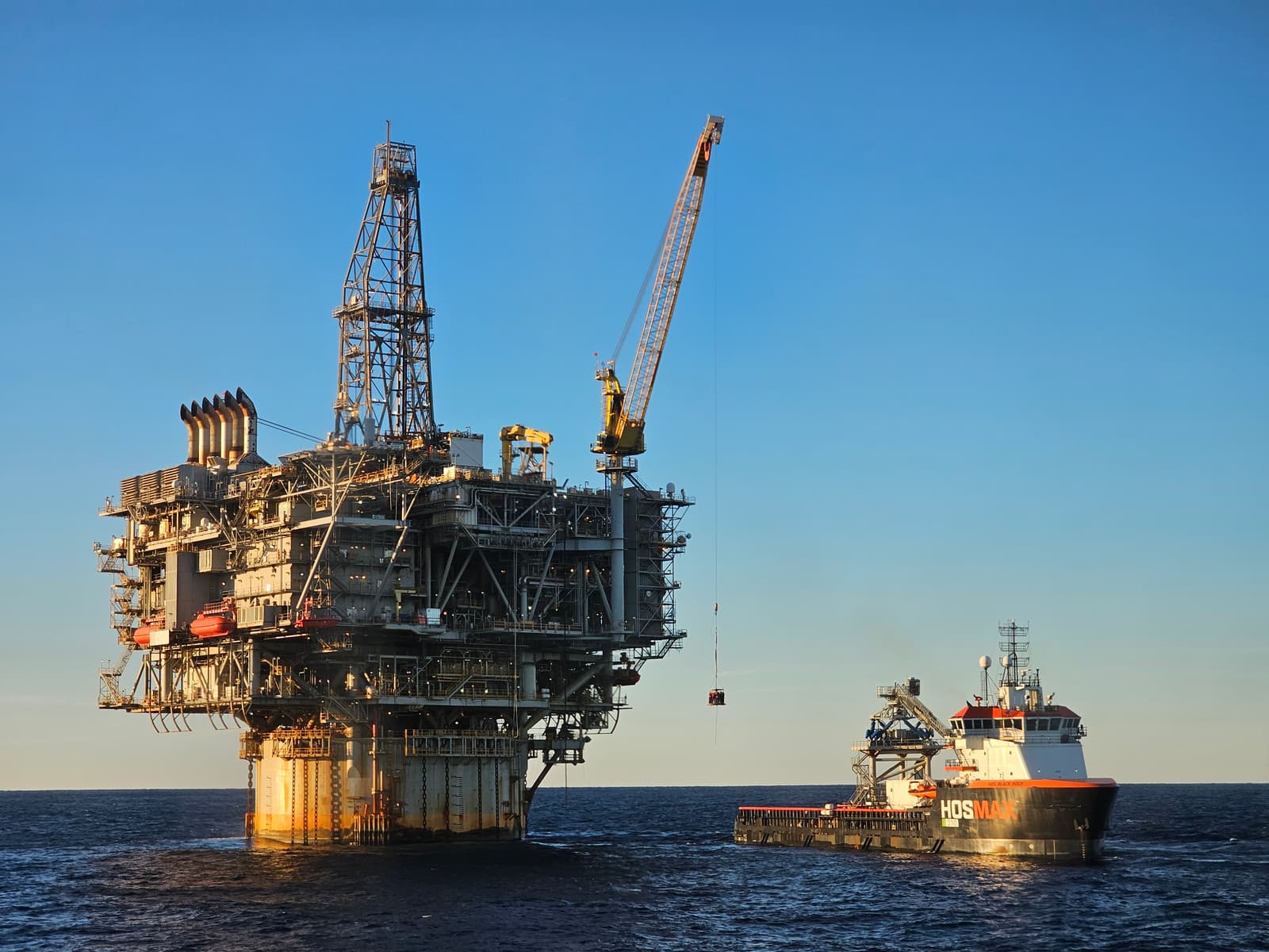 Offshore oil platform and crew transfer vessel, illustrative of upstream energy operations